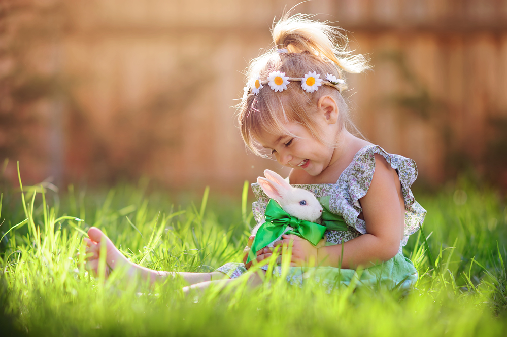 Cute little girl with a bunny rabbit at easter with green grass