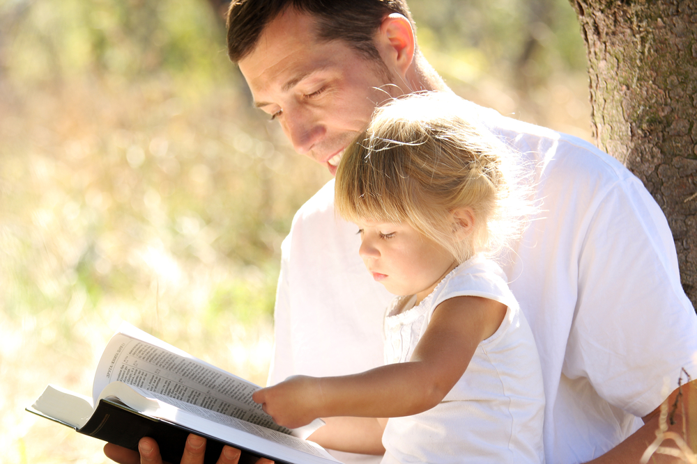 Dad reads Bible with daughter