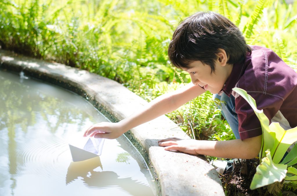 fruit of the spirit peace craft: boy floating a paper boat in a garden pool