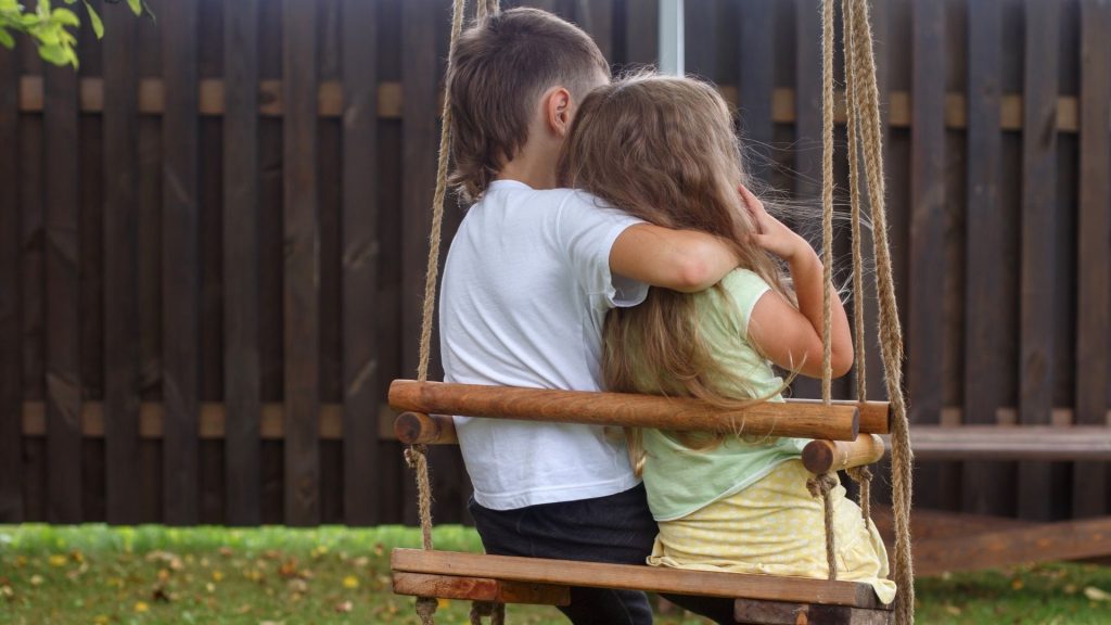 children showing kindness to each other while on a swing